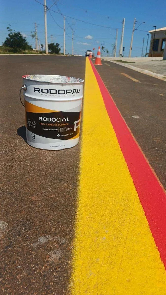Balde de RODOCRYL ao lado de faixas coloridas aplicadas no pavimento